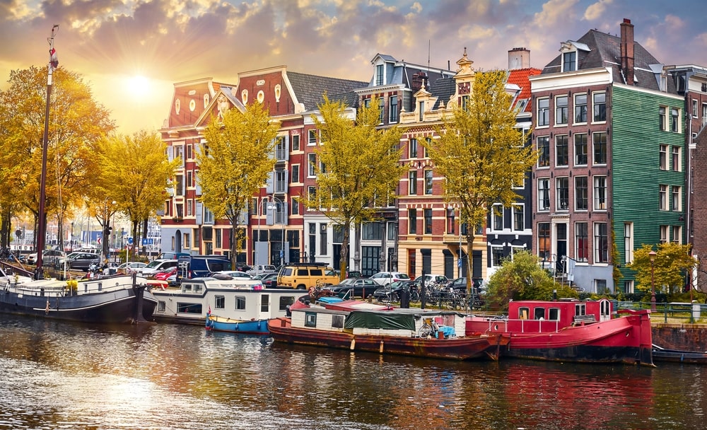 Amsterdam, Netherlands. Panorama of famous dancing houses on river Amstel, water channels with house boats. Popular landmark and travel destination in old european city